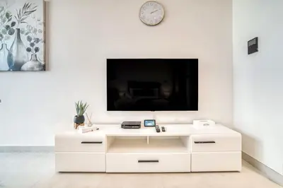 a white cabinet with a tv on a white wall at Bright Studio in Binghatti Canal in Dubai