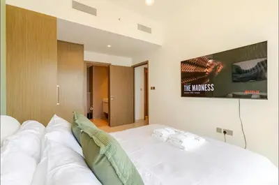 a bedroom with a white bed with a tv on the wall at Full Burj Khalifa View, 3min Walk to Dubai Mall, 29th floor in Dubai
