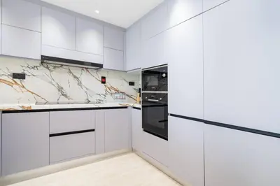 a white kitchen with white cabinets and appliances at High-Floor Upgraded 3-Bed Marina Apartment in Dubai