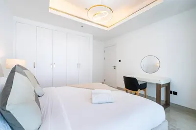 a white bedroom with a bed and a desk at High-Floor Upgraded 3-Bed Marina Apartment in Dubai