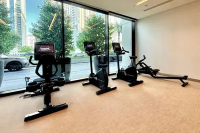 a gym with treadmills and a television in a room with windows at Luxury 1 Bed Apt in Palace, Dubai Creek Harbour in Dubai
