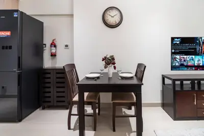 a dining room with a table and a clock on a wall at Stylish and Spacious Downtown Studio in Dubai