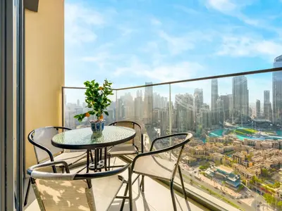 a table and chairs on a balcony with a view of a city at Iconic Burj and Fountain View 2BR Downtown in Dubai