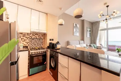 a kitchen and living room with a view of the ocean at HAVN - Studio in Al Jawhara, JVT in Dubai