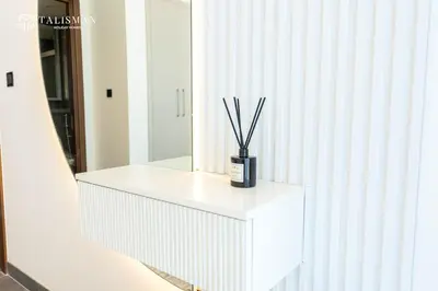 a white cabinet with a vase with sticks in it at Luxury 1BR Burj Khalifa & Flamingo Sanctuary Views in Dubai