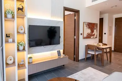 a living room with a dining room table and a television at Luxury 1BR Burj Khalifa & Flamingo Sanctuary Views in Dubai