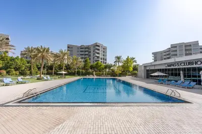 a swimming pool at a resort with palm trees and buildings at Brand New Designer Space with All Modern Amenities in Dubai