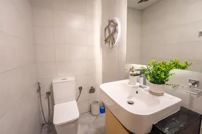 a bathroom with a white toilet and a sink at Luxury 1 Bedroom with Pool Dubai Frame Museum View in Dubai