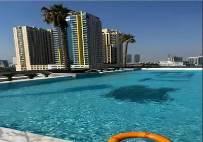 a large swimming pool with buildings in the background at City Forest Studio in JVC in Dubai