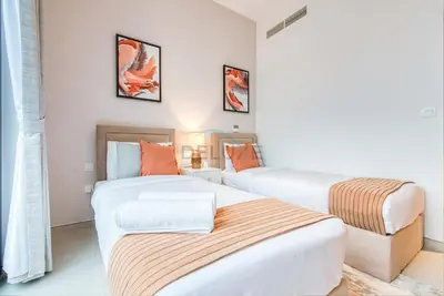 two beds in a room with white walls and orange pillows at Fresh 2BR at Mudon Views 4, Dubailand by Deluxe Holiday Homes in Dubai