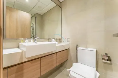 a bathroom with a sink and a toilet and a mirror at Studio Near Meydan Racecourse and Golf Club with Convenient Access to Al Meydan Road and Dubai Top Attractions, Azizi Riviera 29, Al Merkadh by Deluxe Holiday Homes in Dubai