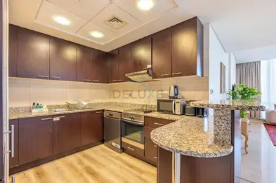 a kitchen with wooden cabinets and granite counter tops at Located Near Museum of the Future and Index Mall, Just a few Minutes Drive from Burj Khalifa and Dubai Mall - Sky Gardens, DIFC by Deluxe Holiday Homes in Dubai