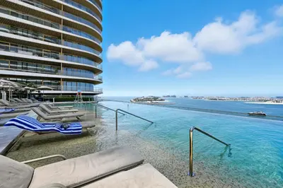 a swimming pool with lounge chairs and a building at Newly Styled 1BD in Grand Bleu Beachfront, Fits 4 in Dubai