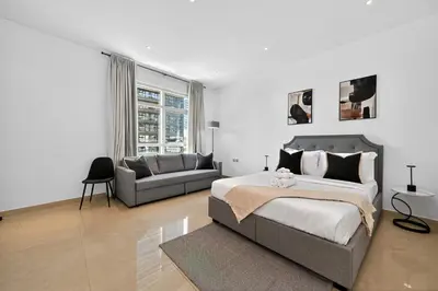 a bedroom with a large bed and a couch at Yacht Bay Tower 1min to Metro, Tram and 5min to Marina in Dubai