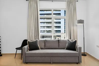 a living room with a couch and a large window at Yacht Bay Tower 1min to Metro, Tram and 5min to Marina in Dubai