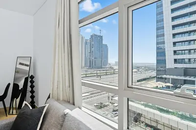 a living room with a couch and a large window at Yacht Bay Tower 1min to Metro, Tram and 5min to Marina in Dubai