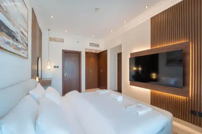 a bedroom with a white bed and a flat screen tv at Downtown Dubai- Modern upgraded 1 BR Plus Study Room with Luxury Interiors and Partial Fountain Views in Dubai