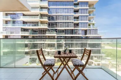 a table and two chairs on a balcony with a tall building at GuestReady - Golf View | Park Access | DAMAC Hills in Dubai