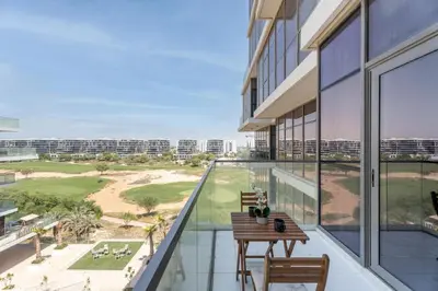 an apartment balcony with a table and chairs and a view of the beach at GuestReady - Golf View | Park Access | DAMAC Hills in Dubai