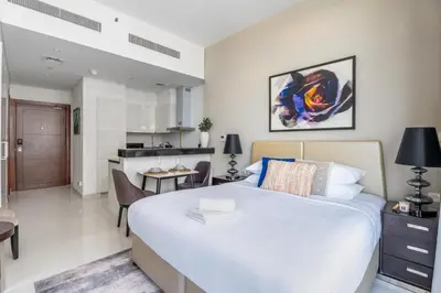 a bedroom with a large bed and a kitchen at GuestReady - Golf View | Park Access | DAMAC Hills in Dubai