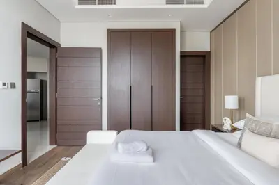 a bedroom with a large white bed with wooden doors at GuestReady - City 1BR | Heart of Business Bay in Dubai