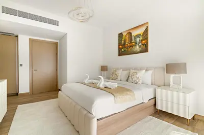 a white bedroom with a large bed and a table at Luxury 4BR and Maid Room Townhouse Tilal Al Furjan in Dubai