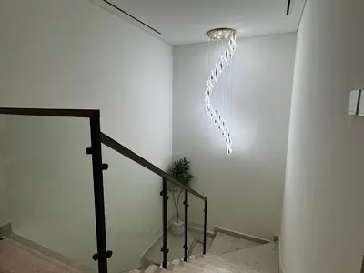 a staircase with a chandelier hanging from a wall at Luxury 4BR and Maid Room Townhouse Tilal Al Furjan in Dubai