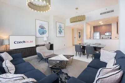 a living room with blue couches and a dining room at Luxury 2BHK Sea & Palm Views 20th Floor Tram line in Dubai