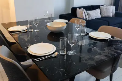 a black table with plates and wine glasses on it at Luxury 2BHK Sea & Palm Views 20th Floor Tram line in Dubai