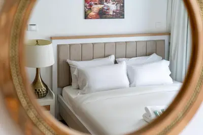 a mirror reflecting a bed with white pillows at New Charming 2BR with Gym & Pool in Azizi Riviera in Dubai