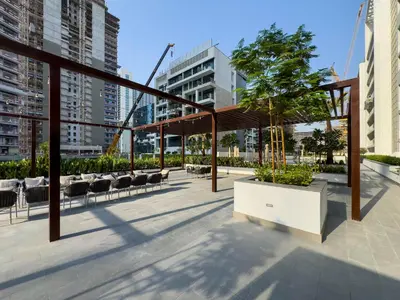 a pavilion with a tree and chairs in a city at New Charming 2BR with Gym & Pool in Azizi Riviera in Dubai