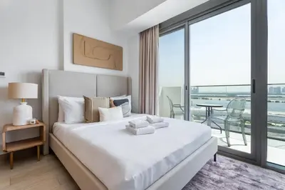 a bedroom with a large white bed with a balcony at GuestReady - Furnished Studio | Burj & Canal Views in Dubai