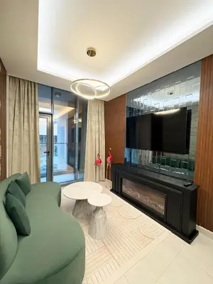 a living room with a green couch and a fireplace at Spacious 1BR JVC Circle Mall at Your Doorstep in Dubai
