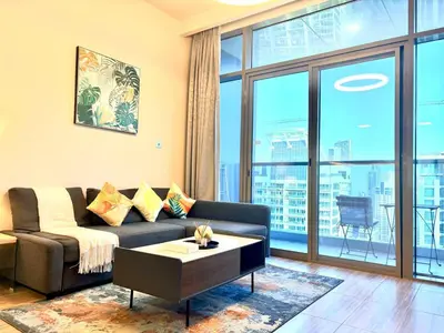 a living room with a couch and a large window at The Greendoor - Lake and Sea View, JLT in Dubai