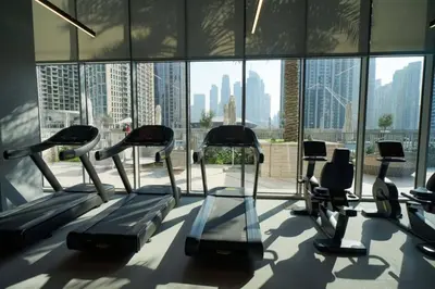 a gym with cardio machines in a large window at Locations l Chic 3 Bedroom l Burj and Fountain Views l Downtown Dubai in Dubai