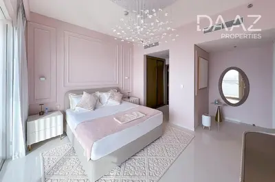 a bedroom with a large white bed and a chandelier at Branded 2BR in Nakhlat Jumeira - Palm View in Dubai