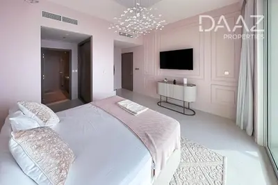 a white bedroom with a large bed and a tv at Branded 2BR in Nakhlat Jumeira - Palm View in Dubai