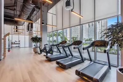 a gym with cardio machines and large windows at Vogue Downtown Forte near Dubai Mall and Burj Khalifa, Three-Bedroom Plus Kids room with Balcony and Fountain view, full access to all amenities in Dubai