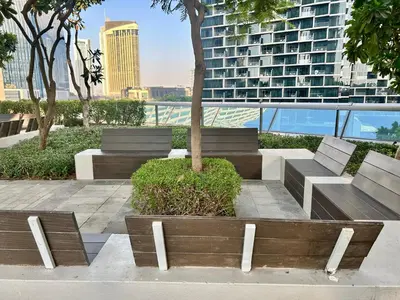 a park with benches and a tree and a building at Private room in 3BR Ultra-Luxury-High-Rise Apartment next to BURJ KHALIFA, DUBAI MALL in Dubai