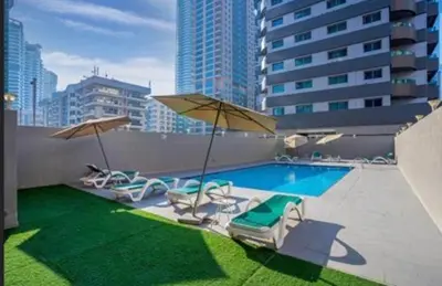 a pool with chairs and umbrellas on a building at Sansa Beach Home in Dubai