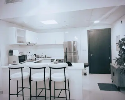 a kitchen with white cabinets and bar stools at Sansa Beach Home in Dubai