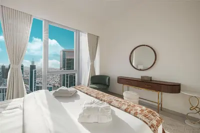 a bedroom with a bed and a mirror and a window at Luxury Grande Suites by Hostiva - Full City View in Dubai