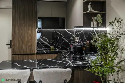a kitchen with a black counter top and chairs at Clever Guest 031 Dubai Gate 2 in Dubai