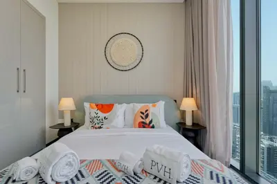 a bedroom with a bed with pillows and a window at PVH Stylish Boho 1BR with Study - The Crest in Dubai