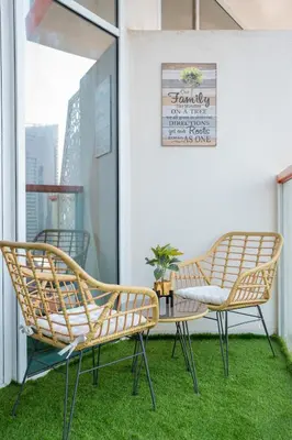two chairs and a table on a balcony with grass at Burjkhalifa View Top Floor Dubai Mall 7Mins in Dubai