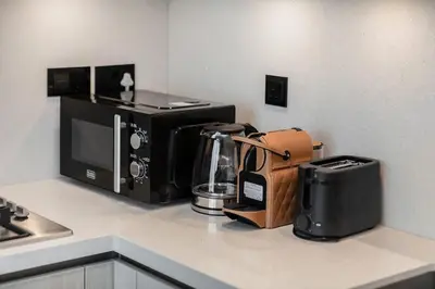 a kitchen counter with a coffee maker and a microwave at Fancy 1BR apartment The Crest at Sobha Hartland in Dubai