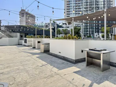a rooftop patio with tables and benches and buildings at Fancy 1BR apartment The Crest at Sobha Hartland in Dubai