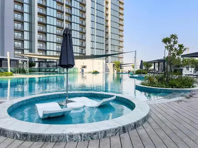 a pool with two white chairs and an umbrella at Fancy 1BR apartment The Crest at Sobha Hartland in Dubai