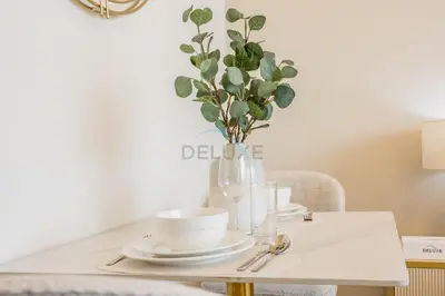 a table with plates and a vase with a plant at Studio with Community Views, Steps from Circle Mall and Parks, Near Jebel Ali Racecourse, Binghatti Azure, JVC by Deluxe Holiday Homes in Dubai