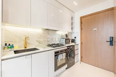 a kitchen with white cabinets and a washer and dryer at Studio with Community Views, Steps from Circle Mall and Parks, Near Jebel Ali Racecourse, Binghatti Azure, JVC by Deluxe Holiday Homes in Dubai